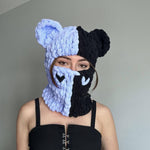 Person wearing a blue and black knitted balaclava with animal ears against a plain background